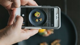 Cineva fotografiază o farfurie cu mâncare gourmet prezentată perfect