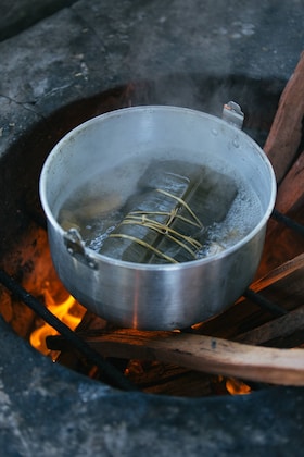O cratiță cu apă fierbând pe un foc de lemne