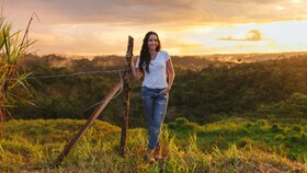 Catalina Vélez stând într-un câmp luminat la apus